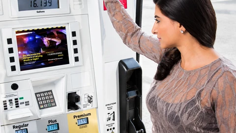 Woman at a fuel pump with a HERO digital advertising display